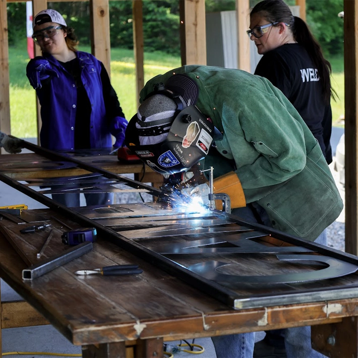 An image of women welding a sign together on table outside
